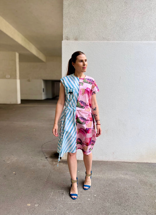 Woman wearing an asymmetric dress with a striped pattern on one side. Watercolor florals on the other side.