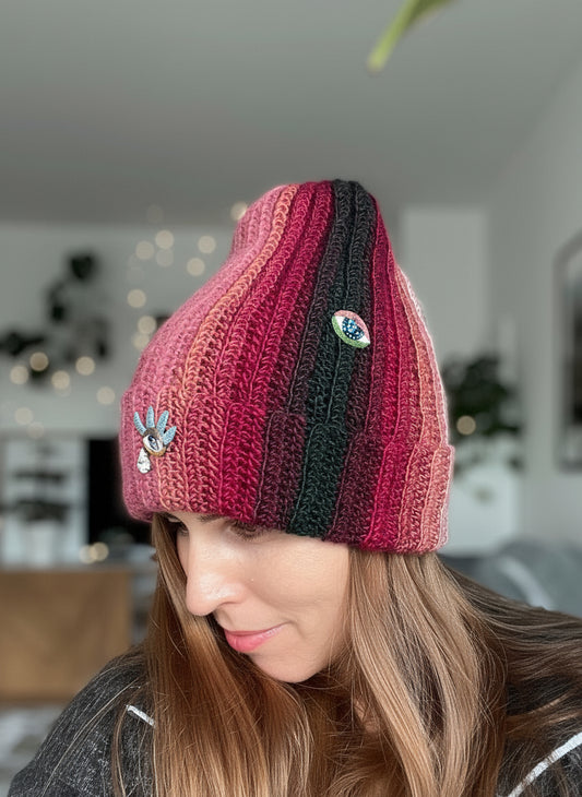 Person wearing a colorful knit beanie with a decorative button indoors.