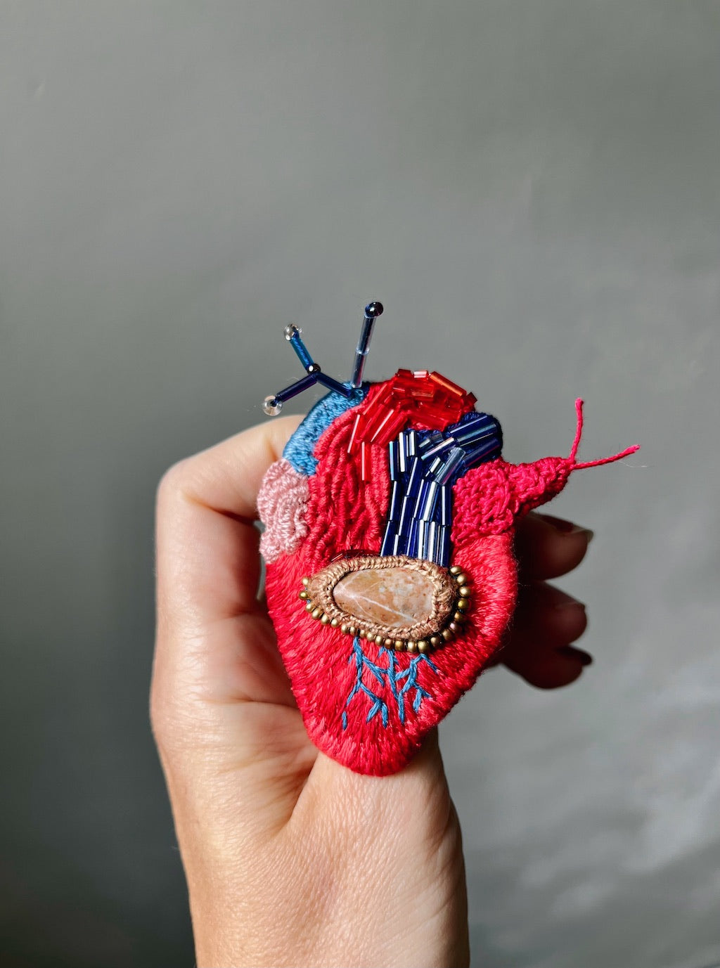 Hand-embroidered heart brooch with brown stone center and glass beads, handmade in Vienna