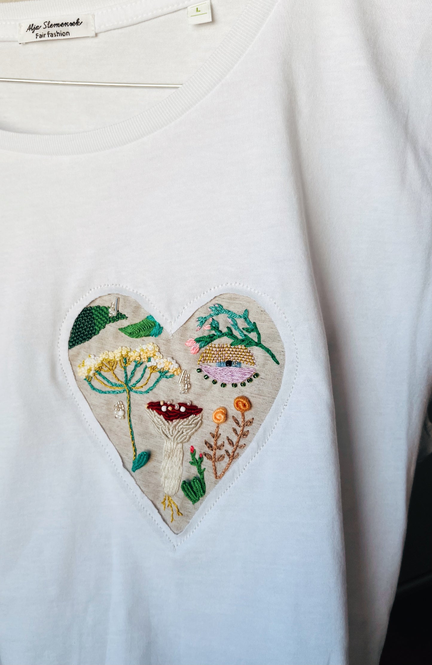 White t-shirt with embroidered heart featuring mushroom and wildflowers design