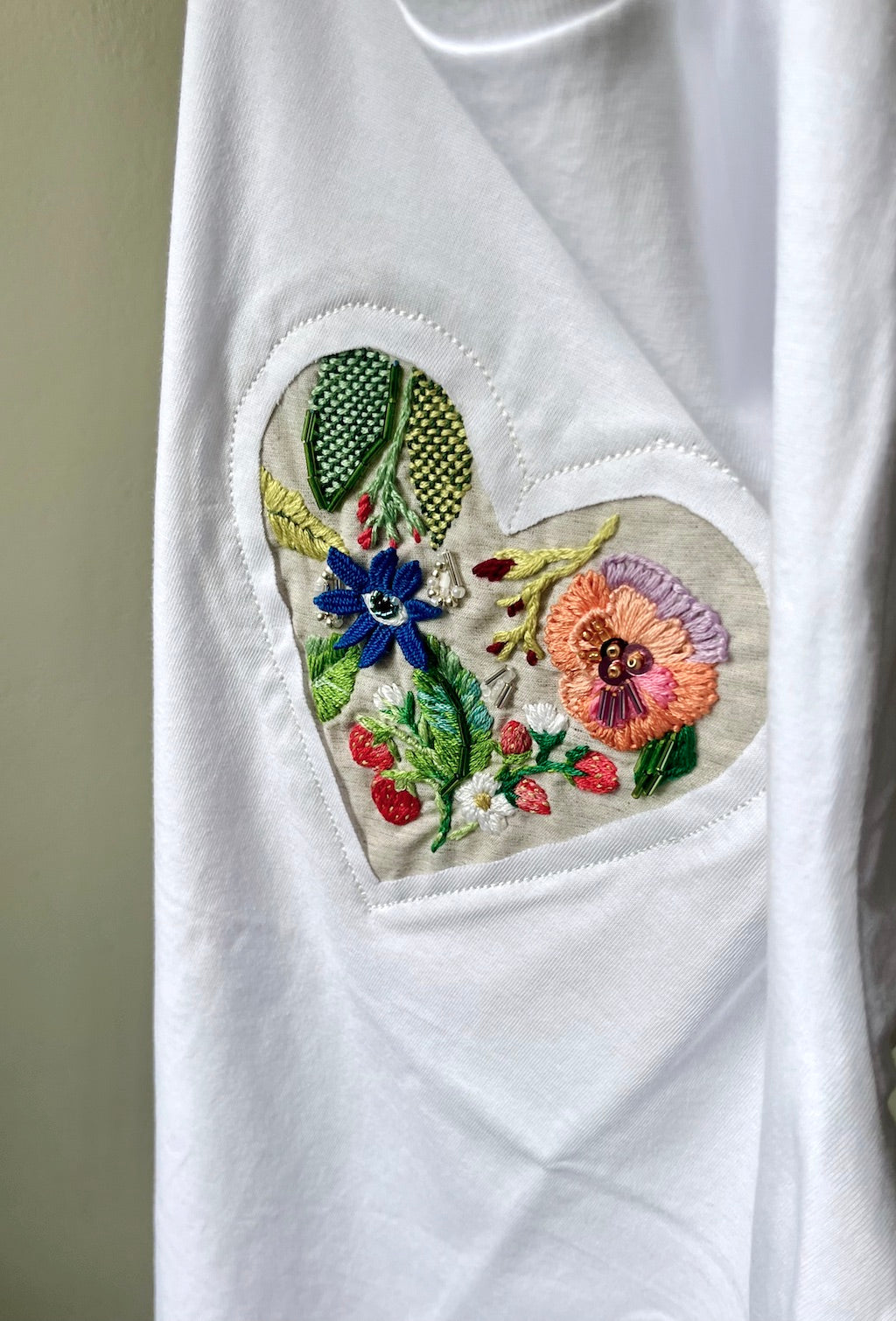 White t-shirt with strawberry flowers embroidery on a plain background