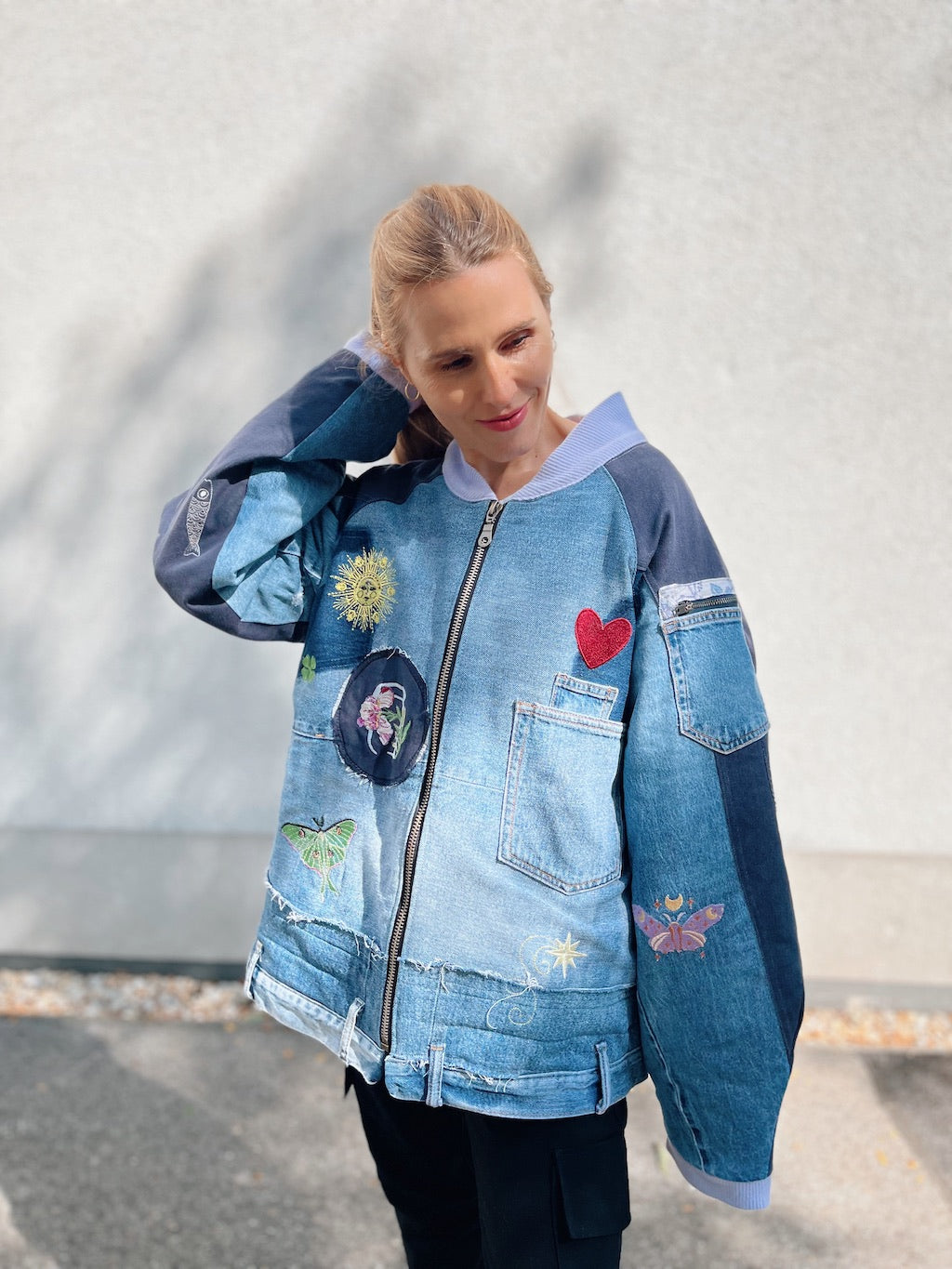 Patchwork blue denim bomber jacket with colourful embroidery, reused jeans pockets and a front zip.