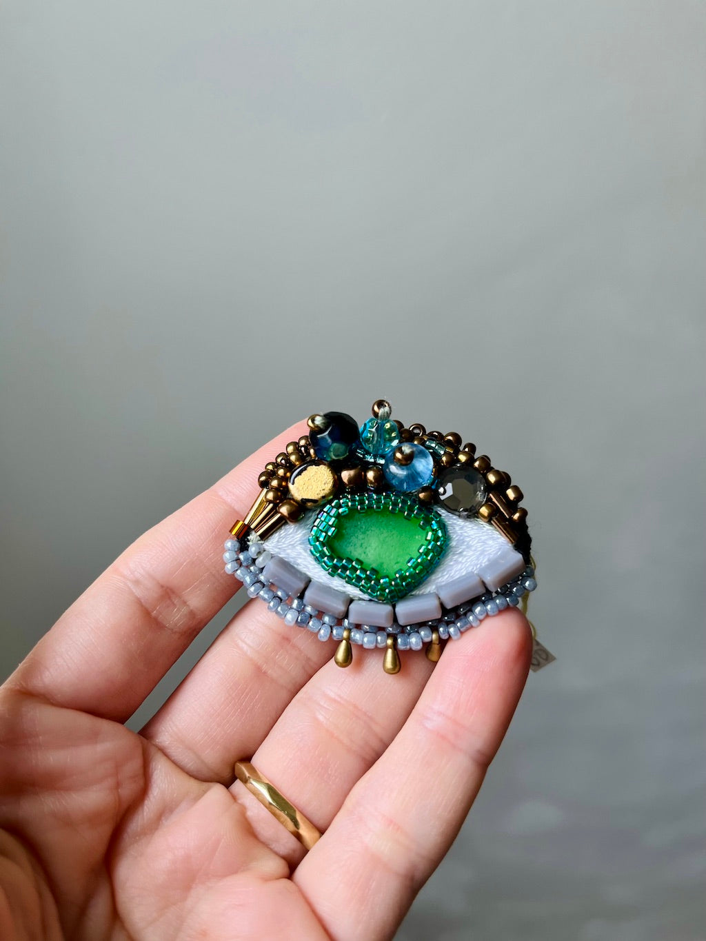 Hand-embroidered eye brooch with green sea glass and Miyuki beads, handmade in Vienna
