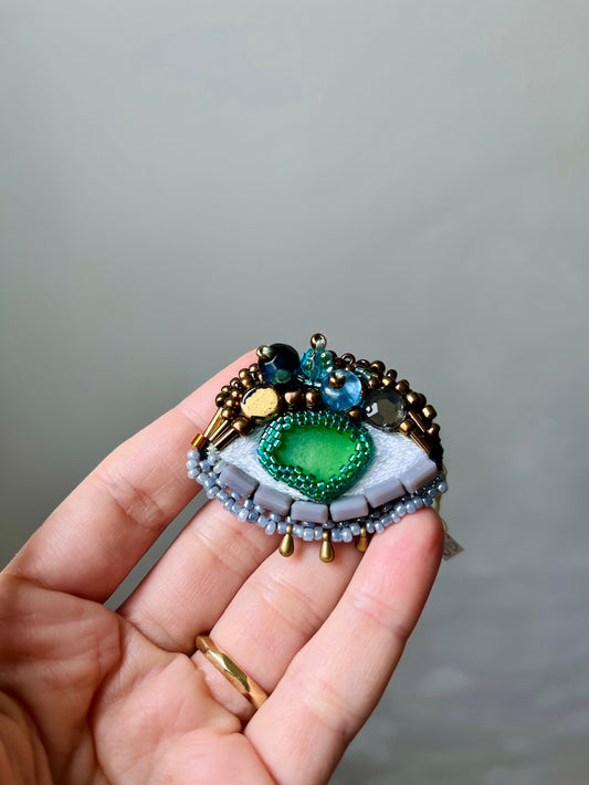 Hand-embroidered eye brooch with green sea glass and Miyuki beads, handmade in Vienna
