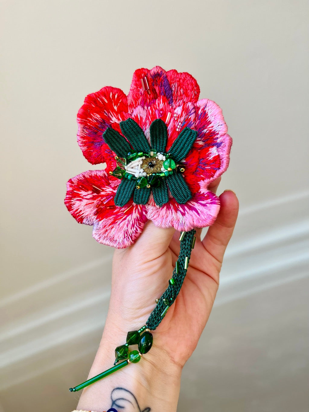 Hand-embroidered flower statement brooch in pink, featuring an eye at the bloom's center